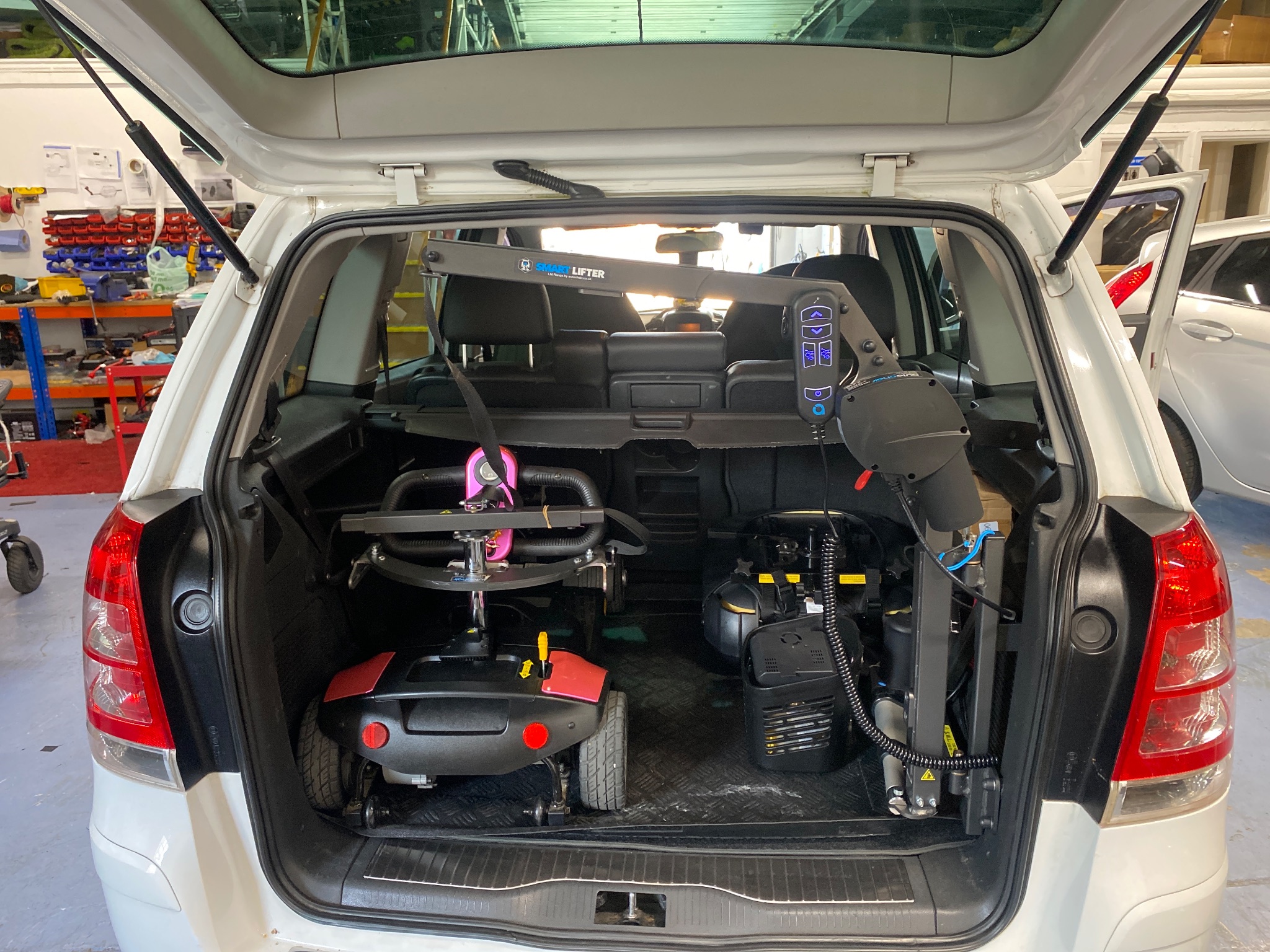 Mobility scooter being loaded into a car boot using an electric hoist