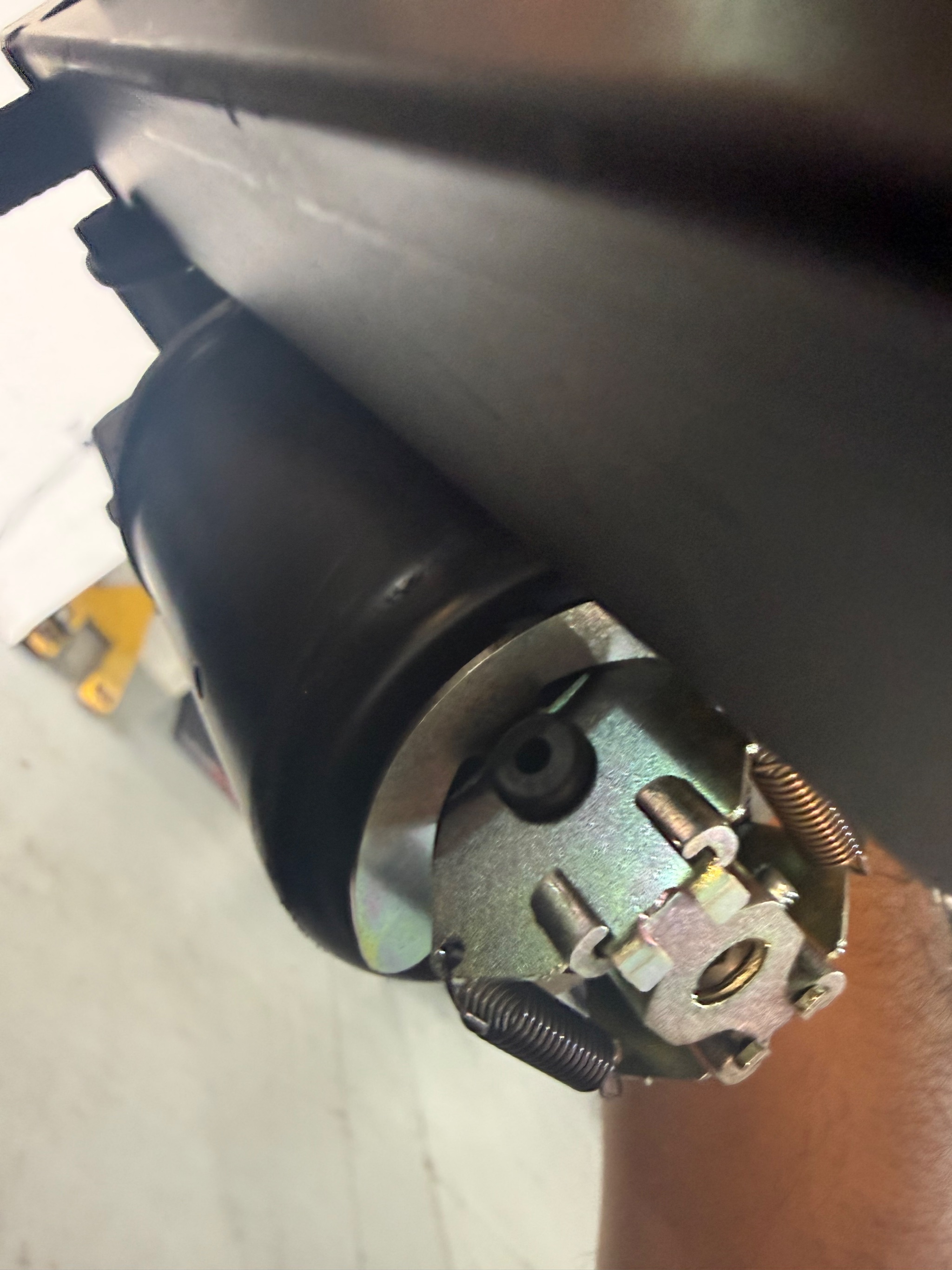 Technician inspecting a vehicle boot hoist motor and gear mechanism