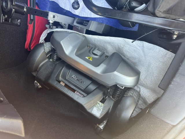 Powered boot hoist arm extended over the rear bumper of the vehicle